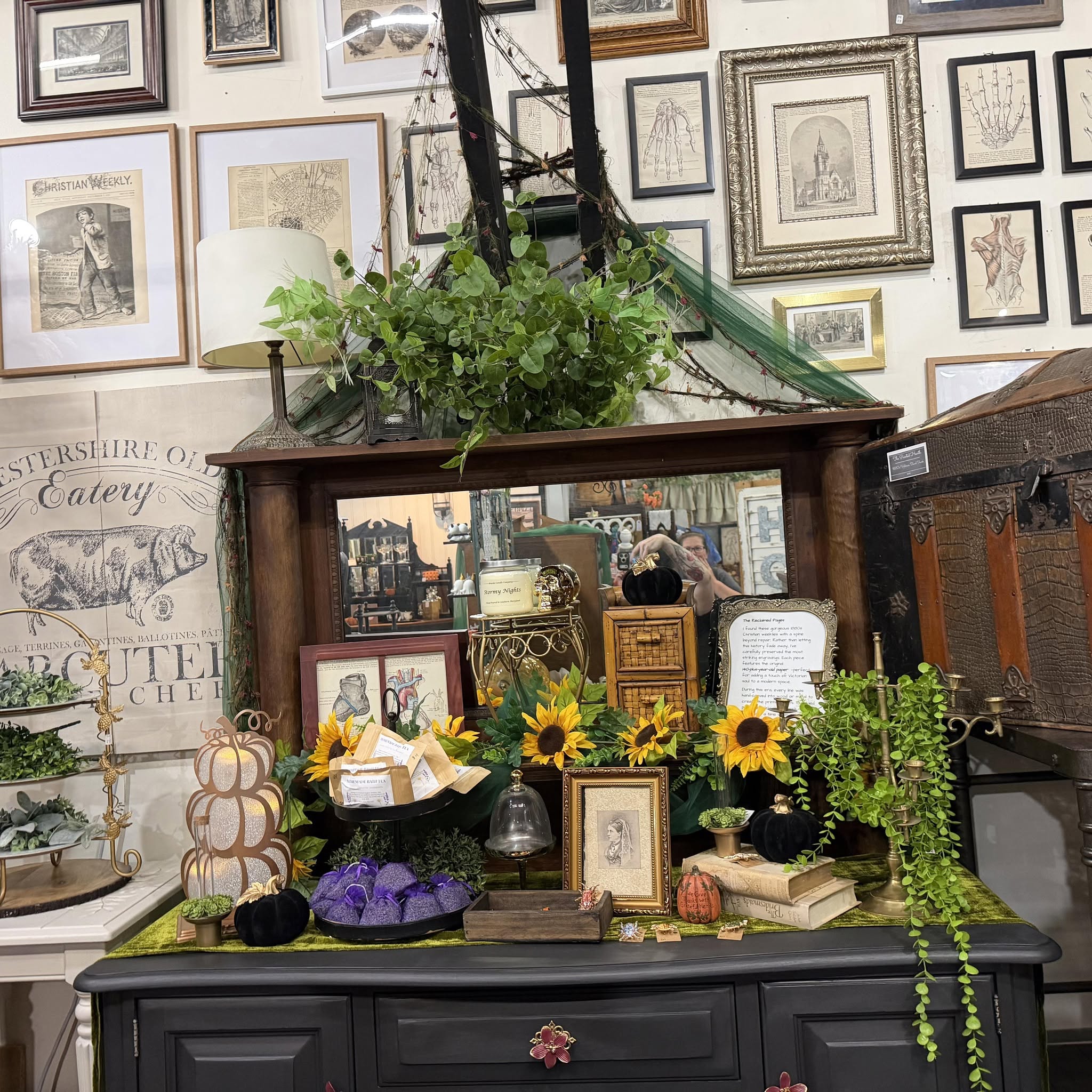The Painted Hearth display with vintage artwork, refinished furniture, greenery, and handmade treasures